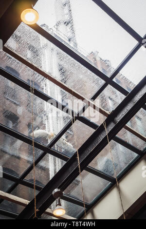 Giorno di pioggia sotto il tetto di vetro di un edificio nella città di New York Foto Stock
