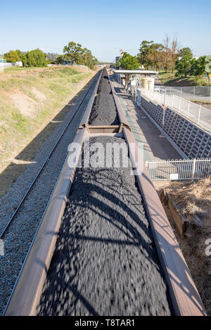 Un treno di carbone sul Nuovo Galles del Sud Settentrionale principale linea passa attraverso Aberdeen stazione ferroviaria in alto la Hunter Valley, Australia Foto Stock