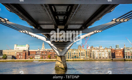 Vista parte inferiore del Millenium Bridge guardando oltre il Tamigi verso la città di Londra Foto Stock