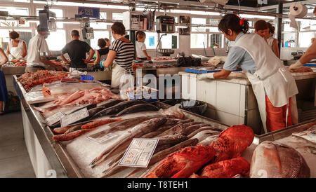 Vista del mercato del pesce in Ciutadella de Menorca, con vari pesci colorati per la vendita, i cartellini del prezzo in primo piano e i clienti turistici Foto Stock