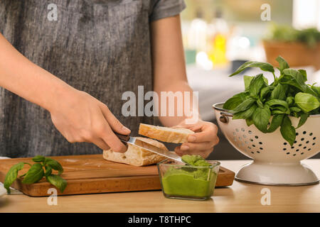 Donna diffusione di basilico in salsa di pane in tavola Foto Stock