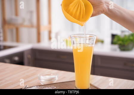 Donna versando spremuta di limone in vetro sul tavolo Foto Stock