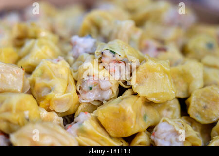 Dimsum cotti al vapore in bambù a street market alimentare in Thailandia, vicino. Dim sum di un piatto cinese di piccole al vapore o fritte gnocchi di salato contenente var Foto Stock