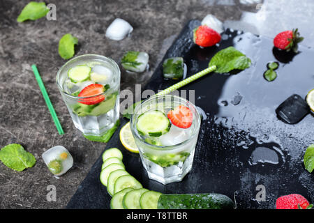 Bicchieri di cetriolo fresco di acqua sulla tabella grigia Foto Stock