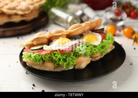 Bolla di deliziosi waffle con uova fritte su piastra Foto Stock