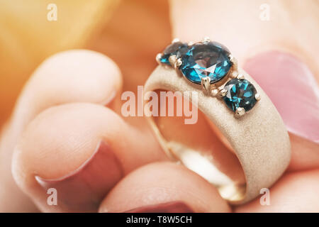 Bellissimo Anello in oro con zaffiro blu in una mano femminile, close-up Foto Stock