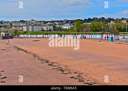 Metà vista la mattina con la bassa marea a Goodrington Sands vicino a Paignton. Multi-colore di cabine sulla spiaggia, fare uno sfondo colorato di rosso la spiaggia sabbiosa. Foto Stock