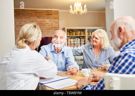 Anziani e un medico o uno psicoterapeuta insieme in una terapia di gruppo Foto Stock