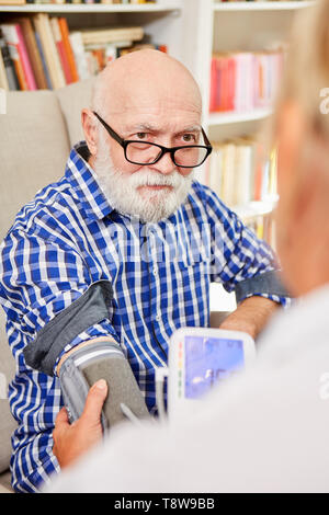La misurazione della pressione sanguigna in un senior con demenza o morbo di Alzheimer presso la casa di cura Foto Stock