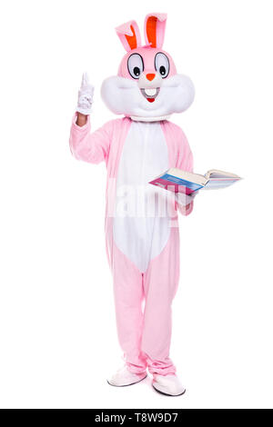 Funny Easter Bunny legge il libro, ottiene un istruzione, cercando di essere intelligente. Dimensioni di vita costume di coniglio con libro su sfondo bianco Foto Stock