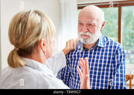 La donna come un medico di famiglia comfort di un uomo anziano con demenza in consultazione Foto Stock