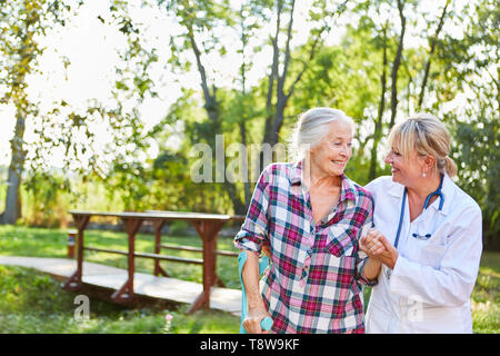 Reha medico o fisioterapista aiuta una donna senior durante l'esecuzione della formazione Foto Stock