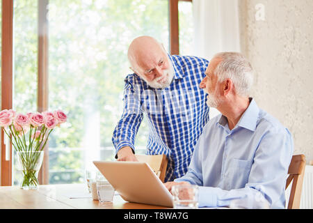 Due anziani come pensionati al computer portatile aiutare se stessi con l'e-learning Foto Stock