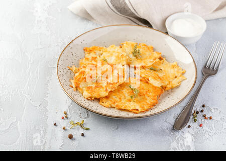 Hommade frittelle di patate - röstinchen, hash browns, kartoffelpuffer, latkes, draniki - con sourcream su sfondo grigio Foto Stock