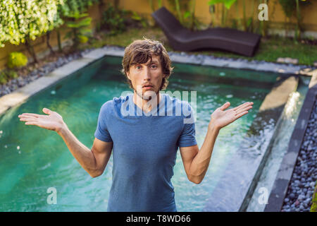 Uomo sceglie i prodotti chimici per la piscina. Servizio piscina e le apparecchiature di pulizia chimica i prodotti e gli attrezzi Foto Stock