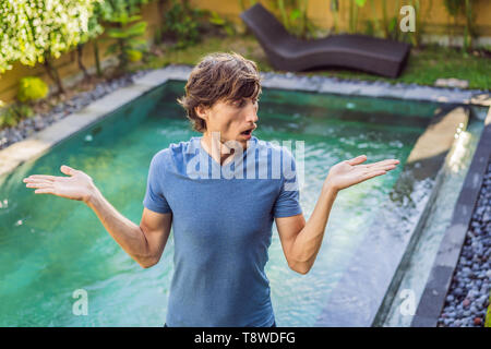 Uomo sceglie i prodotti chimici per la piscina. Servizio piscina e le apparecchiature di pulizia chimica i prodotti e gli attrezzi Foto Stock