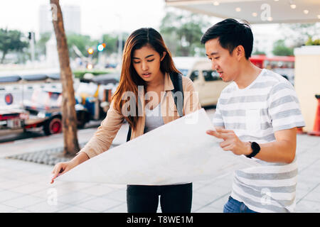 Viaggiare donna asiatica e uomo di lettura sulla mappa Street di Bangkok di esplorare la città insieme, Thailandia Foto Stock