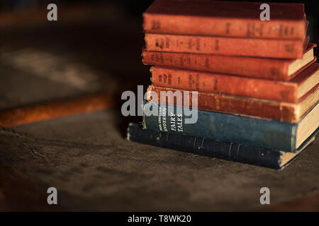 Soft focus immagine di una pila di vecchi vintage libri a copertina rigida con il focus sulle parole Hans Christian Andersen e favole Foto Stock