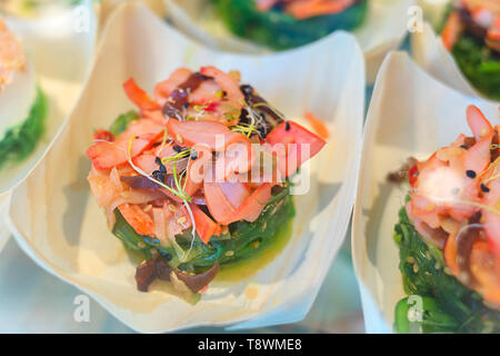 Tapas tradizionali spagnole con piatti a base di pesce fresco servito in tazza piccola - deliziosa calamari con marinata insalata di alghe e si germina di germogli alfalfa Foto Stock