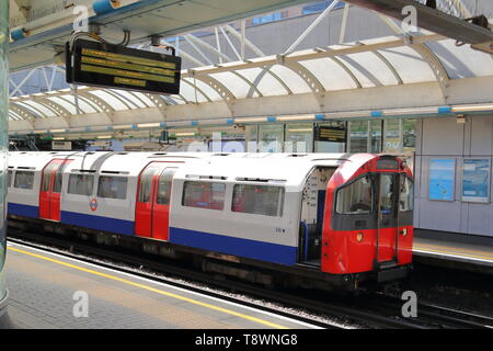 La Metropolitana arriva alla fermata della metropolitana di Hammersmith, London, Regno Unito Foto Stock