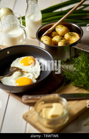 Uovo fritto con giovani di patate con aneto e latte sul tavolo di legno Foto Stock
