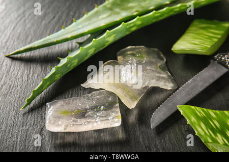 Tagliare Aloe vera con il coltello sul tavolo scuro Foto Stock