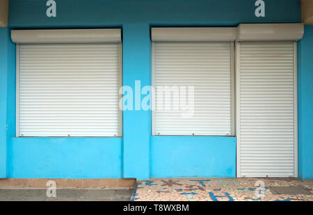 Porta di ingresso e le finestre nell'edificio, protetti da serrande avvolgibili Foto Stock