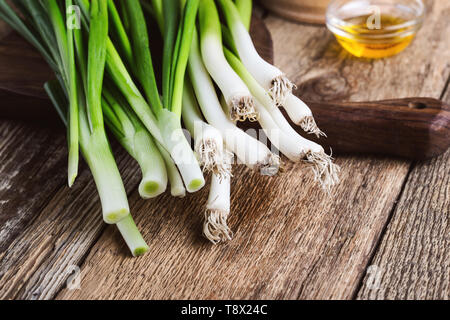 Fresco verde primavera la cipolla e aglio sul rustico sfondo di legno, impianti alimentari a base di ingredienti di cottura Foto Stock