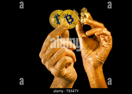 Mani femminili con bitcoins e pepite d'oro su sfondo nero Foto Stock