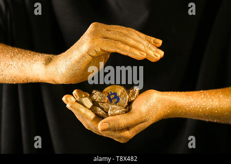 Donna con bitcoin e pepite d'oro su sfondo nero, primo piano Foto Stock