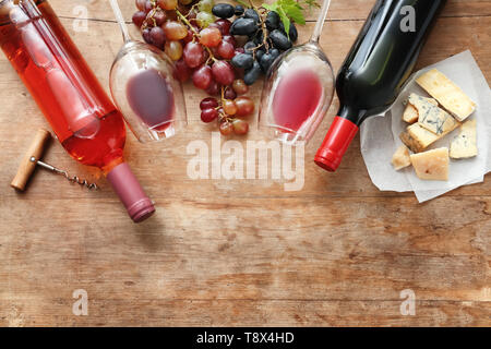 Composizione con vino, uve fresche e formaggio su sfondo di legno Foto Stock