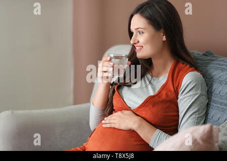 Bella donna incinta acqua potabile a casa Foto Stock