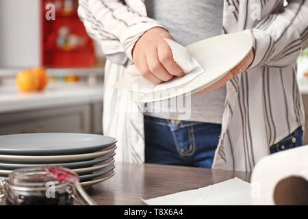 Donna piastra di strofinamento con un tovagliolo di carta in cucina Foto Stock