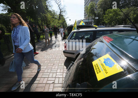 Kiev, Ucraina. 15 Maggio, 2019. Una donna cammina oltre le macchine parcheggiate con i loghi delle ONG ''Auto Euro Power'' su come i proprietari della Comunità-veicoli registrati uniti all'interno di ONG ''Auto Euro Power'' protestare presso Hrushevsky Street nella parte anteriore del parlamento ucraino in Kiev, Ucraina, Maggio15, 2019. Gli attivisti delle ONG di ONG ''Auto Euro Power'' la richiesta di ridurre le accise su sdoganamento delle autovetture usate da Europa e diminuire i prezzi del carburante. Credito: Sergii Kharchenko/ZUMA filo/Alamy Live News Foto Stock