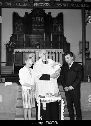 Un bambino del battesimo nel Regno Unito c1962 mamma, papà con il bambino e il vicario all interno della chiesa Foto di Tony Henshaw Foto Stock