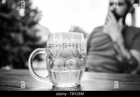 Freddo boccale di birra fresca sul tavolo vicino. L'uomo sedere cafe terrazza godendo di birra sfocato. Alcol e bar concetto. Giovani creativi birraio. La birra artigianale è giovane e urbano e alla moda. Distinta cultura della birra. Foto Stock