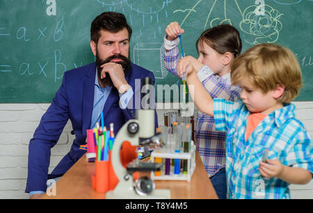 Sviluppo precoce dei bambini. torna a scuola. microscopio strumento ottico a scienza classe. bambini felici insegnante. Imparare mediante microscopio a scuola lezione. Curioso professore a scuola Foto Stock