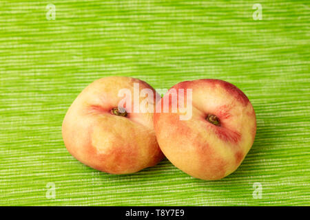 Due pesche piatto dal di sopra su uno sfondo verde Foto Stock