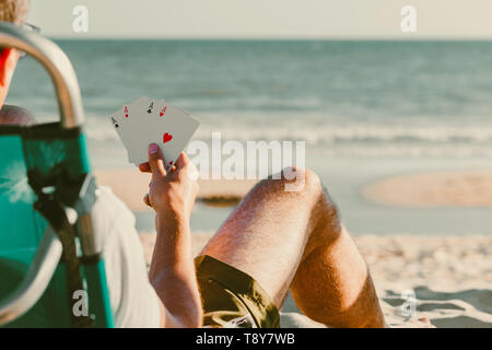 Scheda di gioco all'aperto in spiaggia, quattro assi in mano al giocatore con il mare e il cielo sullo sfondo Foto Stock