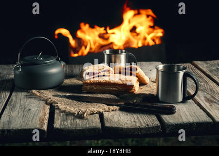 Fine snack per due di notte kamping outdoor - biscotti e tè vicino al caminetto. Foto Stock