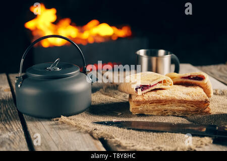 Fine snack per due di notte kamping outdoor - biscotti e tè vicino al caminetto. Foto Stock