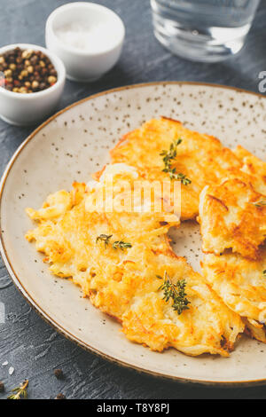 Hommade frittelle di patate - röstinchen, hash browns, kartoffelpuffer, latkes, draniki - con sourcream su sfondo grigio Foto Stock