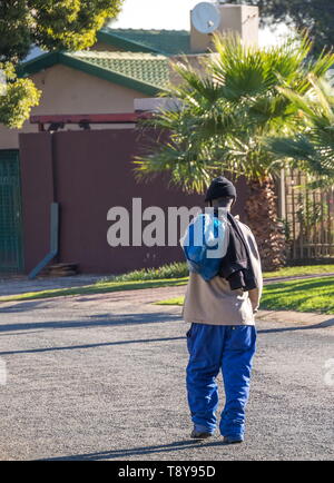 Johannesburg, Sud Africa - anziani non identificato uomo nero passeggiate in casa nel pomeriggio dopo una giornata di lavoro nella città immagine in formato verticale Foto Stock