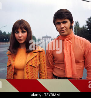 Das Musikerpaar israelische Esther & Abi Ofarim posiert in orangener Kleidung vor dem Brandenburger Tor, Deutschland 1967. Il musicista israeliano giovane Esther & Abi Ofarim in posa di vestiti arancioni davanti alla Porta di Brandeburgo, Germania 1967. Foto Stock