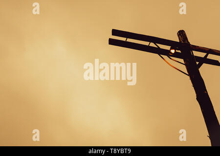 Vecchio vintage railroad lampada piccola lampadina sul legno palo in legno arredo urbano artigianale design idea di vivere la vita giallo orage backgro Foto Stock