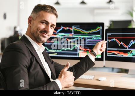 Immagine dell'imprenditore caucasico 30s indossare tuta di lavoro di Office sul computer con grafica e grafici a schermo Foto Stock