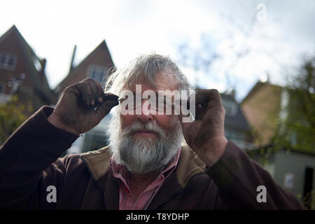 Ritratto di una forma e sani anziani uomo duro sul lavoro giardinaggio in sua iarda posteriore nel sole primaverile Foto Stock