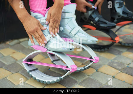 Due donne mettere su kangoo jumping stivali prima di allenamento. Closeup shot con le mani Foto Stock