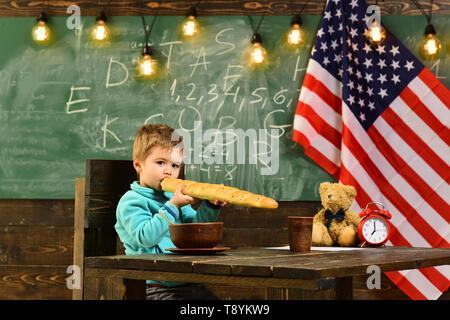 Il patriottismo e la libertà. Little Boy mangiare pane a bandiera americana a conoscenza giorno. Scuola kid alla lezione 4 di luglio. Felice giorno di indipendenza degli Stati Uniti d'America Foto Stock