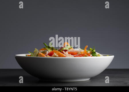 Un sano ciotola di pollo Insalata di pasta e verdure come pepe, foglie di insalata, pomodori, cetrioli, gestire tout e la carota. Foto Stock